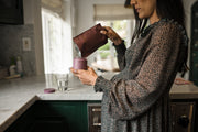 woman refilling bottle of wenatal prenatal - wenatal for her in kitchen - role of vitamin A in pregnancy